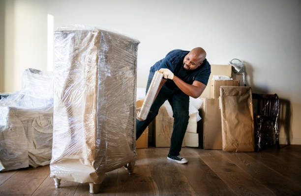 A Forward Thinking Movers team member shrink-wrapping furniture before lifting it, to protect it in transit