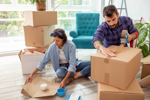 A couple packing and taping moving boxes together at home