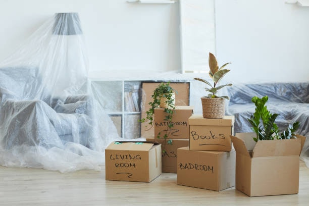 Moving boxes labelled by room with furniture wrapped, packed and ready for moving day